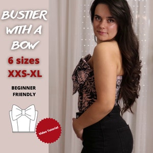 May include: A close-up of a woman wearing a black and pink floral print bustier with a bow. The bustier is strapless and has a fitted silhouette. The text "Bustier with a Bow" is written in white letters on a pink background. The text "6 sizes XXS-XL" is written in white letters on a pink background. The text "Beginner Friendly" is written in white letters on a pink background. A white illustration of a bustier with a bow is shown below the text. The text "Video Tutorial" is written in white letters on a red circle.