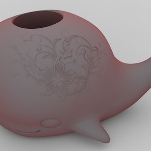 Puede incluir: Un objeto decorativo rosa con forma de ballena con grabados florales. La ballena tiene un cuerpo redondeado, una cola y un orificio de respiración. El texto "Solid Obje." es visible. El objeto parece estar impreso en 3D.