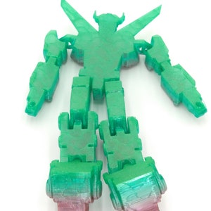 May include: A translucent green and pink robot toy with articulated limbs. The robot has a detailed, textured surface and a stylized design. The legs transition from green to pink. The robot is posed with arms and legs extended.