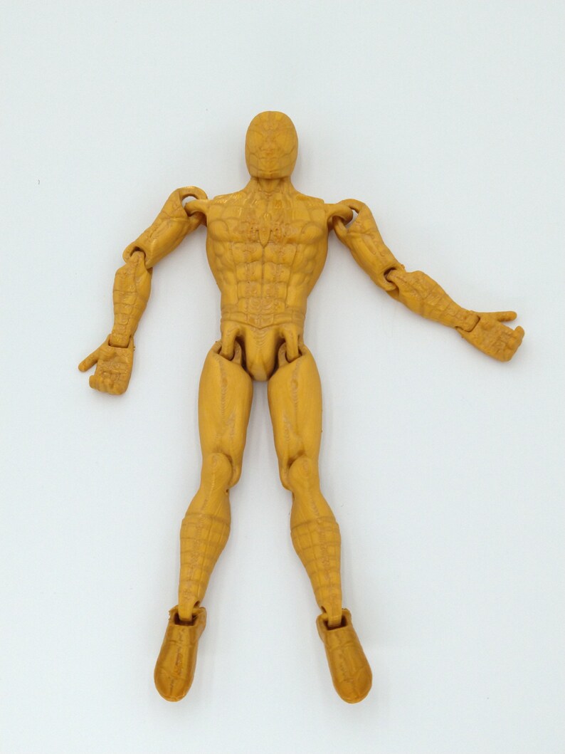 May include: A tan action figure of a superhero with articulated joints. The figure is posed with arms outstretched and legs slightly apart. The figure has detailed musculature and a textured surface.