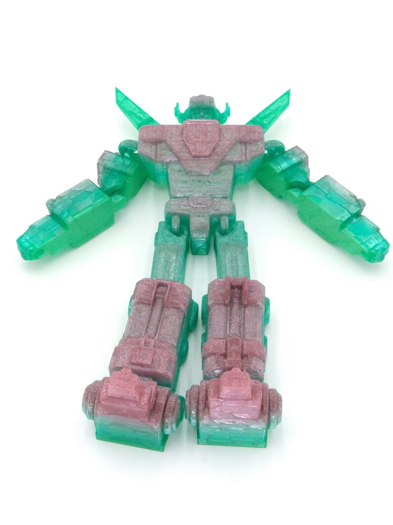 May include: A 3D-printed robot toy in shades of green and pink. The robot has a detailed design with articulated arms and legs, and a head with a distinctive shape. The toy is standing upright against a white background.