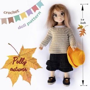 以下が含まれることがあります： 手作りの編み人形。高さ約20cmで、ベージュのセーター、黒いスカート、靴を着用しています。人形は薄茶色の髪で、黄色の帽子を持っています。画像には「crochet doll pattern」と「Polly autumn」というテキストが含まれています。