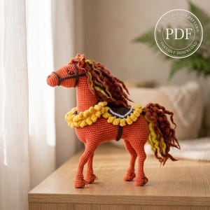 May include: A crocheted orange horse figurine with a yellow and brown saddle and mane. The horse has a detailed design, including a bridle and a decorative collar. The image includes a PDF logo with the words "Instant Download".