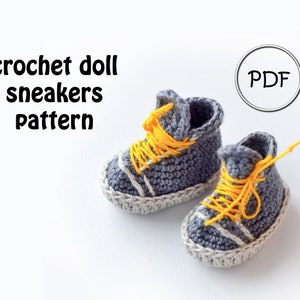 May include: A crochet pattern for doll sneakers. The sneakers are gray with white accents and yellow laces. The pattern is available as a PDF download.