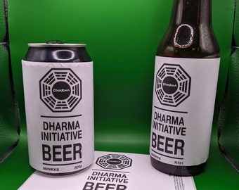 Può includere: Due bottiglie di birra Dharma Initiative, una di vetro e una in lattina, entrambe con un'etichetta in bianco e nero con il logo Dharma Initiative e il testo "Dharma Initiative Beer".