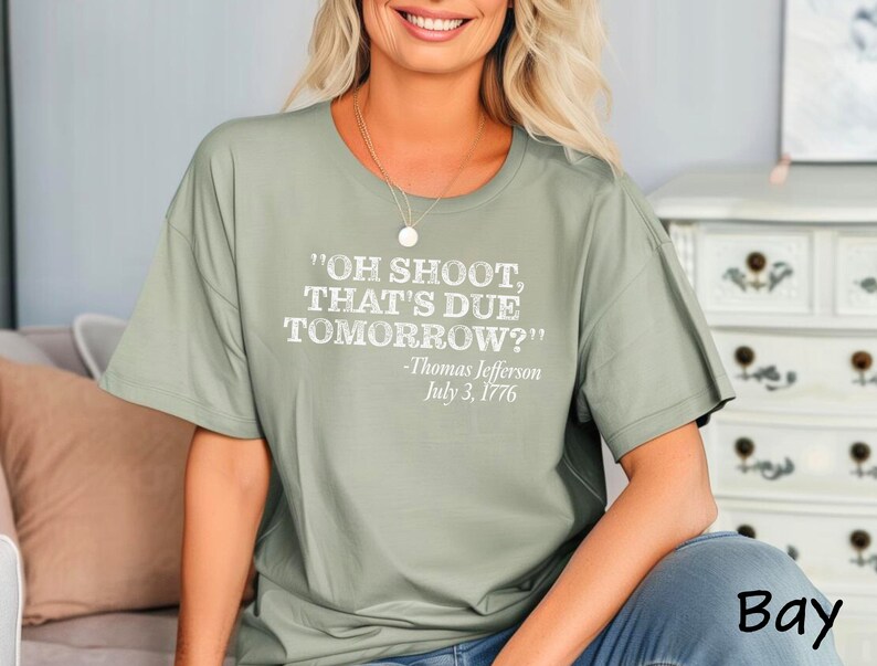 May include: Sage green t-shirt with a white graphic print that reads "OH SHOOT, THAT'S DUE TOMORROW?" -Thomas Jefferson July 3, 1776