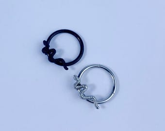 May include: Two hoop earrings, one black and one silver, each featuring a snake design. The snake is coiled around the hoop, adding a unique and edgy touch to the jewelry. The earrings are set against a light blue background.