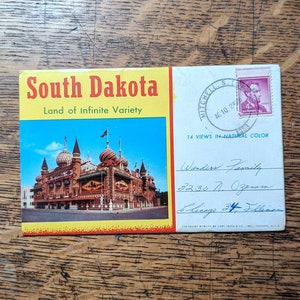 May include: Vintage postcard of South Dakota with a colorful image of a building with onion domes. The postcard has the text "South Dakota Land of Infinite Variety" and a postage stamp.