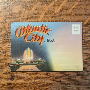 May include: Vintage postcard featuring a colorful illustration of the illuminated fountain of light in Atlantic City, New Jersey. The postcard has a place for a stamp and an address.
