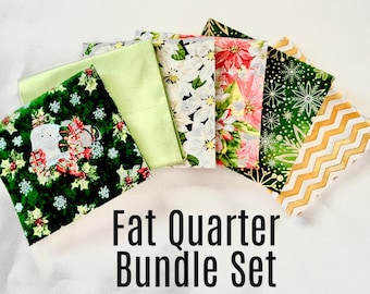 May include: A set of six fat quarter fabric squares. The fabrics feature a variety of holiday-themed patterns, including green and white snowflakes, red and green holly, and gold and white zigzags. The fabrics are perfect for quilting, crafting, and other sewing projects.