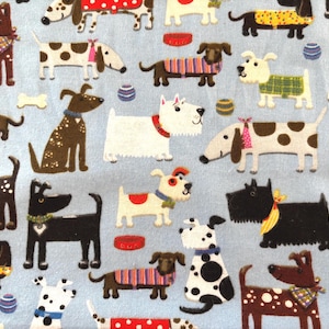 May include: A light blue fabric featuring a repeating pattern of various cartoon dogs. The dogs are in different poses and colors, some with spots, wearing bandanas, sweaters, and collars. There are also bone and ball illustrations.