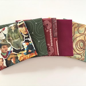 May include: A collection of fabric items with various patterns and colors. The items include a collage of vintage cowboy images, dark green with white dots, burgundy paisley, solid burgundy, rope design, and solid green.