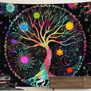 May include: A vibrant tapestry featuring a colorful tree of life design, surrounded by suns, moons, and stars on a black background. The tree has rainbow-colored branches and roots, with chakra symbols. The tapestry is a decorative wall hanging.