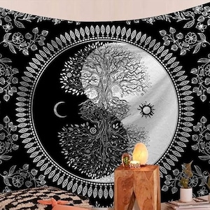 May include: Black and white tapestry featuring a Yin and Yang design with a tree of life, moon, and sun. The tapestry has a floral border and is suitable for wall decor. The design is detailed and intricate, creating a striking visual.
