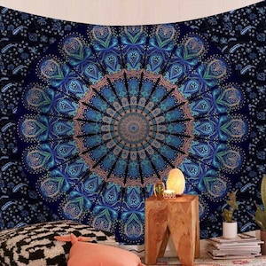 May include: A large, dark blue tapestry with a central mandala design in shades of blue, teal, and peach. The mandala features intricate floral patterns radiating outwards. The background is a darker blue with a repeating floral pattern. The tapestry is likely used for wall decor.
