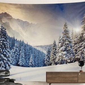 Op de afbeelding: Een wandtapijt met een winterberglandschap met besneeuwde dennen. De afbeelding toont een besneeuwd bos en een bergketen onder een blauwe en gele lucht. Het wandtapijt creëert een serene en natuurlijke sfeer.