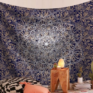 Könnte beinhalten: Ein marineblauer Wandteppich mit einem großen weißen Mandala-Design. Das Mandala hat komplizierte Details und ist von einem kleineren floralen Muster umgeben. Der Wandteppich hängt an einer Wand und davor stehen einige Dekorationsartikel.