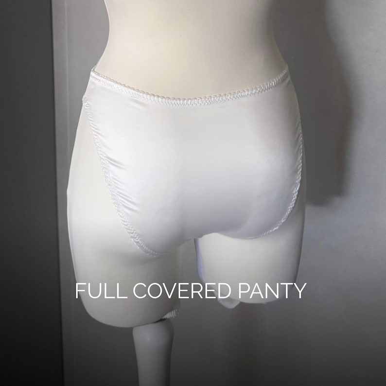 May include: A pair of white satin knickers with a high-cut leg design and elasticated trim along the waist and leg openings. The garment features a smooth, solid white finish and includes the text FULL COVERED PANTY printed in white at the bottom.