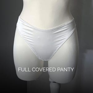 May include: A pair of white knickers featuring a smooth, solid-coloured fabric with a subtle sheen. The garment has a high-cut leg opening finished with a delicate, decorative white trim along the edges. The text FULL COVERED PANTY is visible.