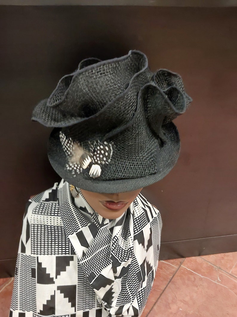 May include: A black, ruffled, wide-brimmed hat with a small, white, polka-dotted feather accent.