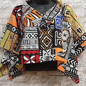 Könnte beinhalten: Ein kurzärmeliges Poncho-Oberteil mit einem lebendigen Patchwork aus geometrischen und abstrakten Mustern in Schwarz, Weiß, Orange, Rot, Gelb und Blau. Das Kleidungsstück hat einen weiten Kragen, eine lockere Passform und einen Saum mit Spitzen.