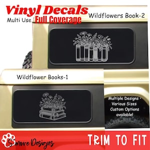 May include: Two black vinyl decals applied to a vehicle window. The top decal features a line art illustration of a row of books with wildflowers. The bottom decal shows a stack of three books with wildflowers. Text includes Vinyl Decals and Wildflowers.