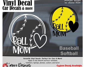 May include: Two vinyl decals featuring a softball design with a heart and the text Ball Mom. One decal is white, and the other is yellow with black text and a black heart. The image includes text stating Vinyl Decal, Car Decals & more, Baseball, Softball, and S'more Designs.
