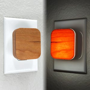 May include: A wooden night light plugged into an electrical outlet. The light is off in the first image and on in the second image, illuminating the wood with a warm orange glow.