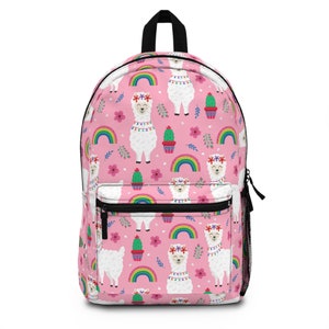 May include: A pink backpack featuring a repeating pattern of white llamas with floral crowns, colorful rainbows, green cacti in pots, and small pink flowers. The bag includes a black top handle, black zippers, and a black mesh side pocket.