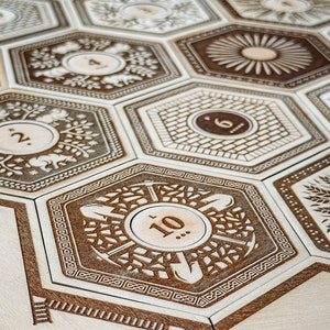 May include: A wooden game board with hexagonal tiles featuring different designs and numbers. The tiles are arranged in a honeycomb pattern. The numbers on the tiles range from 2 to 10.