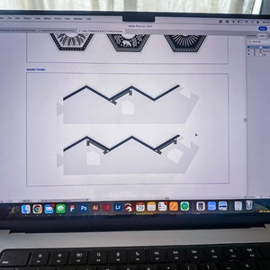 May include: A laptop computer screen displaying a design program with a white background and black lines forming a zig-zag pattern. The screen also shows a row of icons at the bottom.