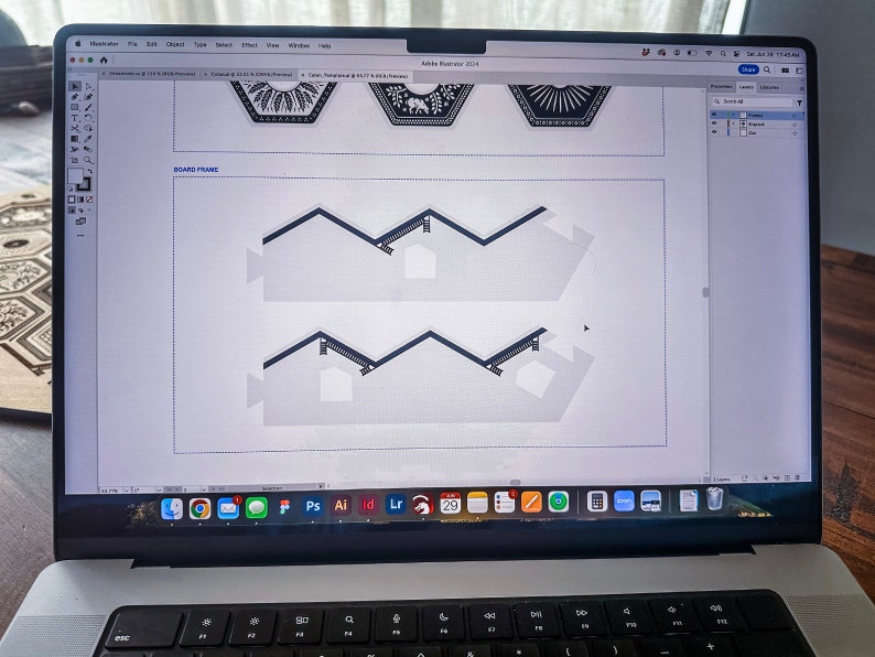 May include: A laptop computer screen displaying a design program with a white background and black lines forming a zig-zag pattern. The screen also shows a row of icons at the bottom.