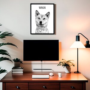 May include: Black and white illustration of a Shiba Inu dog with the name "Wakai" printed above the dog. The illustration is framed and hanging on a white wall above a desk with a computer monitor, a keyboard, a lamp, and plants.
