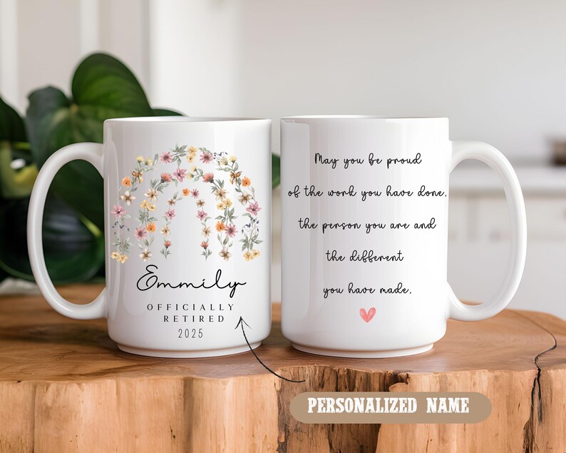 Peut inclure: Une tasse &agrave; caf&eacute; en c&eacute;ramique blanche avec un motif floral et le texte "Emmily Officially Retired 2025". L'autre c&ocirc;t&eacute; de la tasse a le texte "May you be proud of the work you have done. The person you are and the different you have made." avec un petit c&oelig;ur rose.