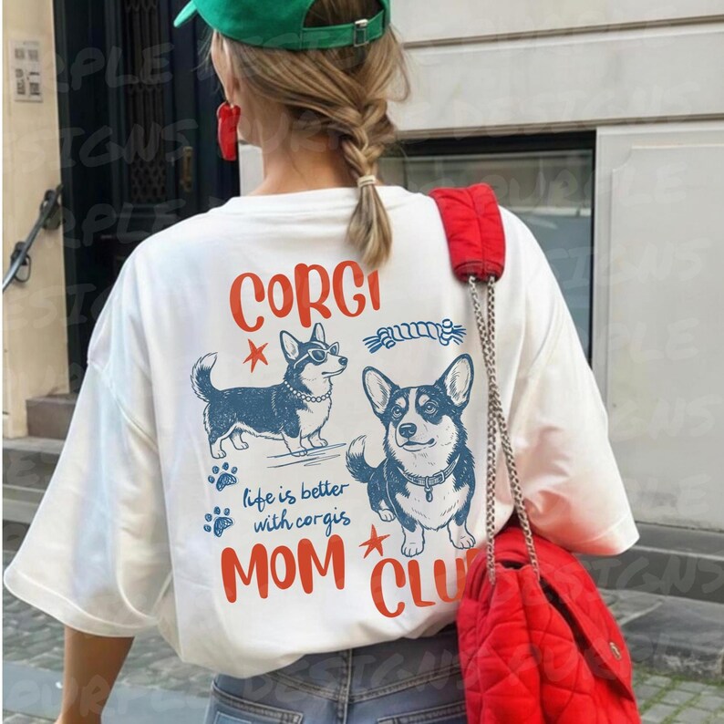 Puede incluir: Camiseta blanca con un gr&aacute;fico de dos corgis, uno con gafas de sol. El texto en la camiseta dice "CORGI", "life is better with corgis" y "MOM CLUB" en rojo y azul. Se ve un bolso rojo.