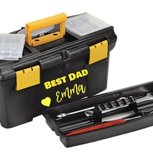 May include: Black toolbox with yellow accents, handle, and latches. The text "BEST DAD Emma" is displayed on the front, along with a yellow heart. A separate tray with tools is included.