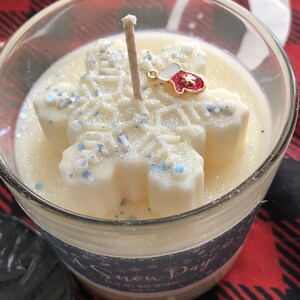 Puede incluir: Vela perfumada "Snow Day" en un tarro de cristal transparente. La vela presenta un dise&ntilde;o de copo de nieve blanco con detalles de purpurina azul y un peque&ntilde;o dije de mit&oacute;n. La vela tiene una mecha.