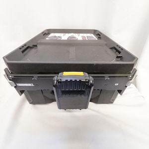 Könnte beinhalten: Schwarze und graue TOUGHBUILT Werkzeugkiste mit gelbem Akzent am vorderen Verschluss. Die Werkzeugkiste hat eine sechseckige Form und ist für die Werkzeugaufbewahrung konzipiert. Der Markenname ist seitlich sichtbar.