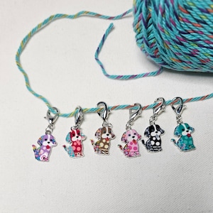 Pu&ograve; includere: Sei marcapunti a forma di cane colorati con chiusure argentate. I marcapunti sono appesi a un filo turchese e giallo.