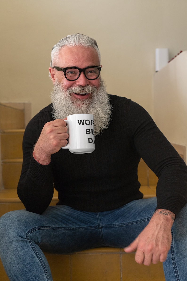 May include: A man with a white beard and glasses is sitting on stairs holding a white mug with the text "Work, Be, Done" printed on it.