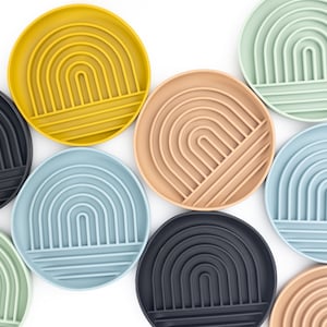 May include: A set of nine silicone trays in various colors, including black, yellow, light blue, green, and beige. Each tray features a raised, concentric arch design.