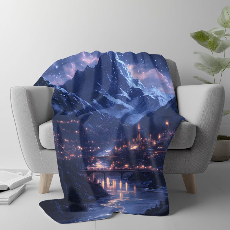 May include: A blue and white throw blanket featuring a fantasy landscape with mountains, a city, and a river. The blanket has a detailed illustration of a nighttime scene with lights and stars.