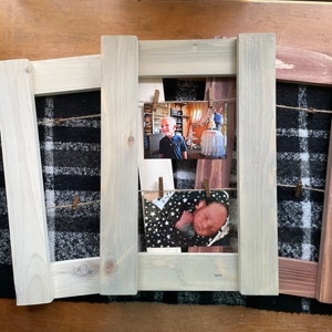 May include: Three wooden picture frames with a rustic, weathered finish. The frames are arranged side-by-side and have twine strung across the front with clothespins holding photos. The frames are on a black and white plaid surface.