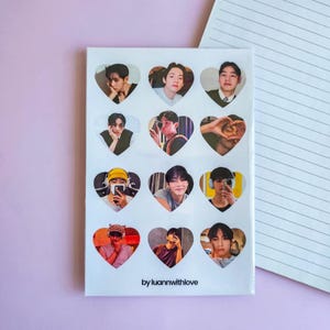 以下が含まれることがあります： 人物の写真が写ったハート型の切り抜きがある白いノート。ノートの右側には罫線入りの紙のデザインがあります。「by luannwithlove」の文字が下部に印刷されています。