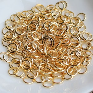 May include: A large pile of gold jump rings. The rings are small and round, and they are ideal for jewellery making.