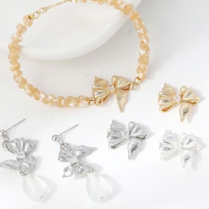 Conjunto de 4 pingentes delicados de laço, em latão banhado a ouro 14k, para confecção de bijuterias.