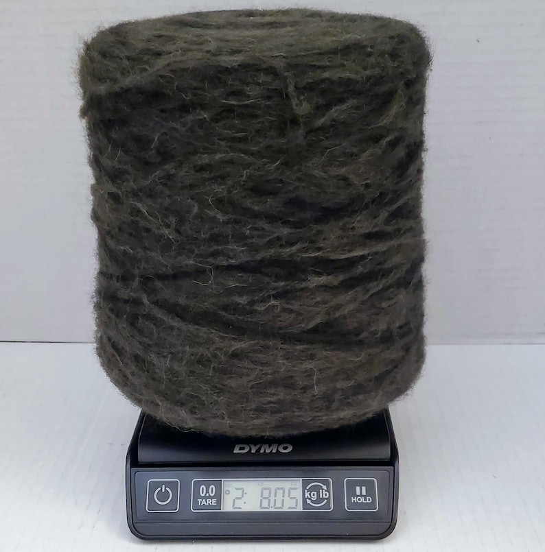 May include: A large spool of dark green yarn is sitting on a digital scale. The scale reads 2.805 kg or 6.19 lb.