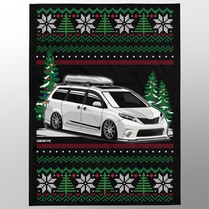 Op de afbeelding: Zwarte deken met een kersttrui-ontwerp. De deken toont een witte minivan met een dakdrager, omringd door kerstbomen en sneeuwvlokken. De tekst "TUNERHYPE" is onderaan zichtbaar.