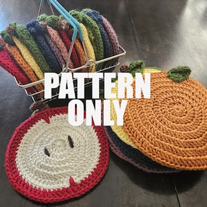 May include: A collection of colorful, crocheted fruit-shaped coasters, including apples and oranges, are displayed. The coasters are in a wire basket and stacked on a dark surface. The text "PATTERN ONLY" is overlaid on the image.