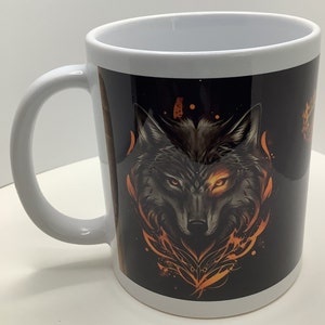 May include: White ceramic coffee mug with a black wolf graphic. The wolf's eye is glowing orange and the background is black with orange flames.